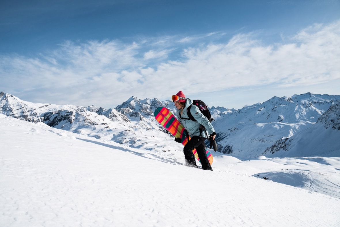 Freeride snowboarder walking through snow in mountains above Val d'Isere